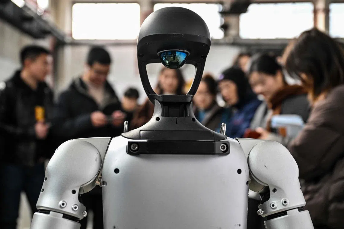 People standing next to a humanoid robot from Unitree Robotics during the Global Developer Conference, organised by the Shanghai AI Industry Association, in Shanghai, on Feb 21, 2025. 