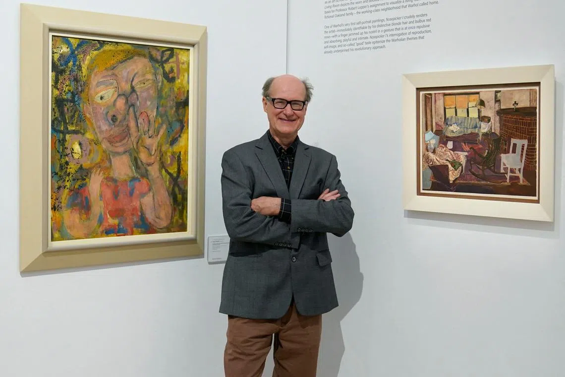 James Warhola, US artist and illustrator, stands next to his uncle Andy Warhol’s Nosepicker 1: Why Pick On Me and Living Room on display at Phillips Auction House in New York. 