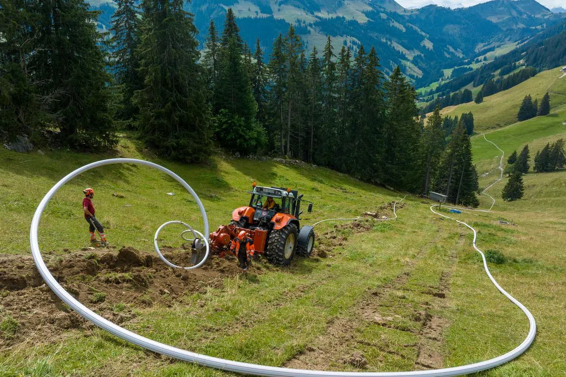 A new water pipe and electrical system is installed for dairy farms in an area where helicopters have been used to take water to some cows so they can continue to graze on alpine pastures, near Jaun, Switzerland, Aug 31, 2023. 