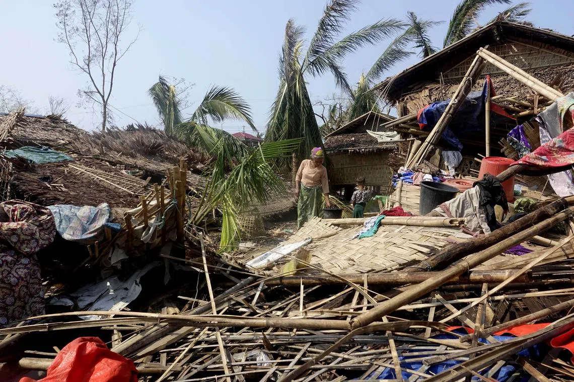 A Rohingya woman stands near a damaged house at the Thae Chaung Muslim internally displaced people camp in Myanmar on May 17.