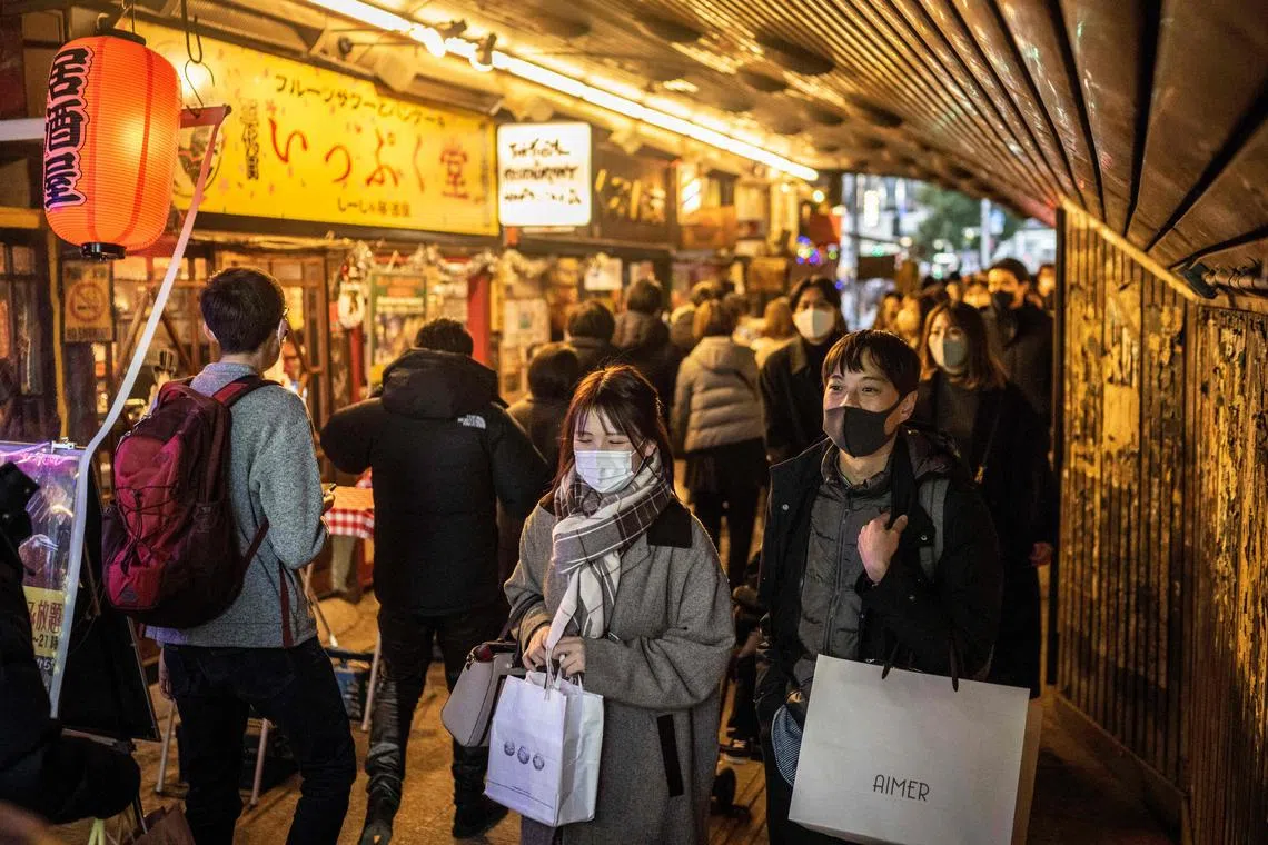 People walk through a street in Yurakucho district of Tokyo on December 24, 2022. (Photo by Yuichi YAMAZAKI / AFP)
