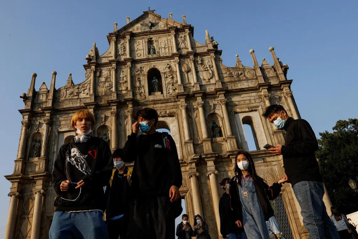 People wearing face masks stand in front of the ruins of Saint Paul's during the coronavirus disease (COVID-19) pandemic in Macau, China, December 29, 2022. REUTERS/Tyrone Siu