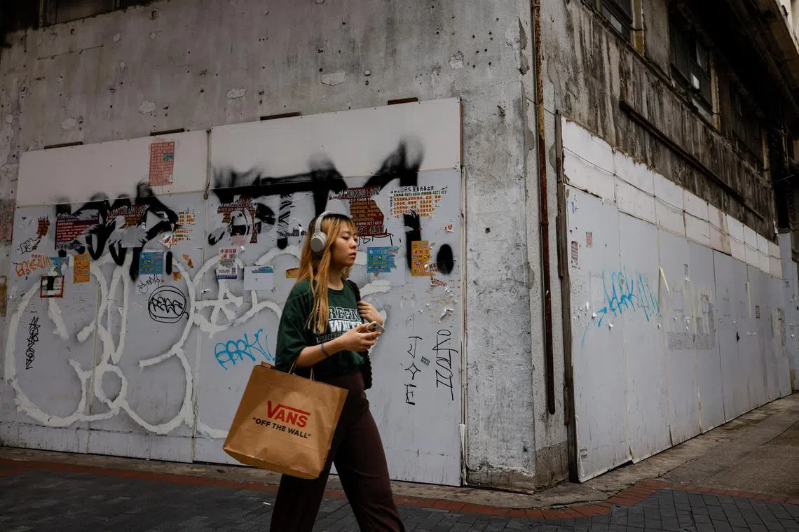 A woman walks past a closed-down retail shop in Tsim Sha Tsui, Hong Kong.