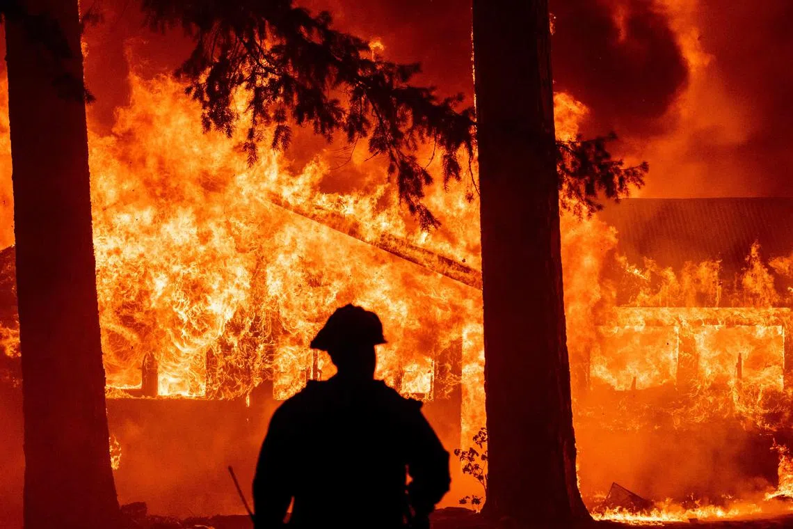 (FILES) Firefighters attempt to get control of the scene as dozens of homes burn during the Dixie in the Indian Falls neighborhood of unincorporated Plumas County, California on July 24, 2021. Natural disasters destroyed assets worth more than $140 billion in the United States last year, of which close to $90 billion was insured, according to data from Munich Re. In California, for example, insurance premiums are well below the national average at around $1,300, according to III, due in large part to state laws that give the government a greater say over any increases. (Photo by JOSH EDELSON / AFP)