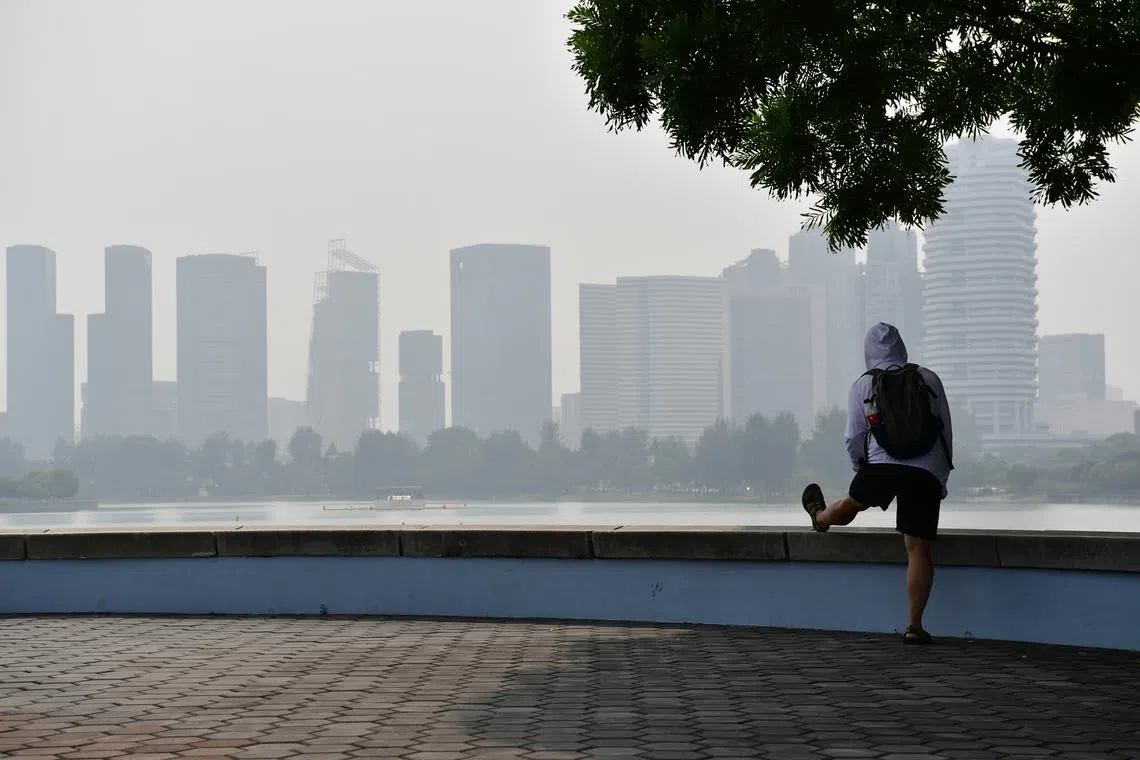 A man outside Singapore Sports Hub stretching his leg against a hazy skyline on Oct 7 at around 3pm. The 24-hour PSI as of 3pm in the south was 95.