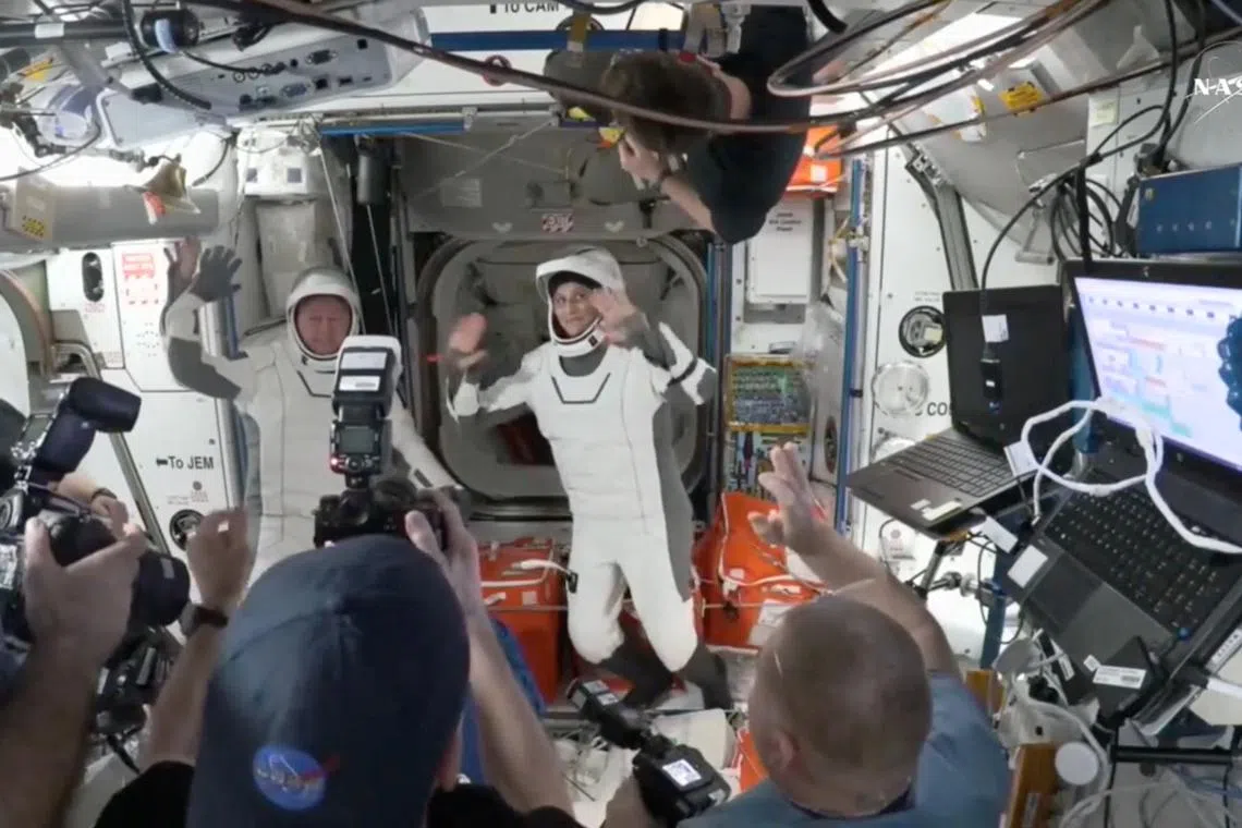 Capt Butch Wilmore and Capt Suni Williams wave at the hatch of a SpaceX Crew Dragon capsule before they begin their return to Earth .