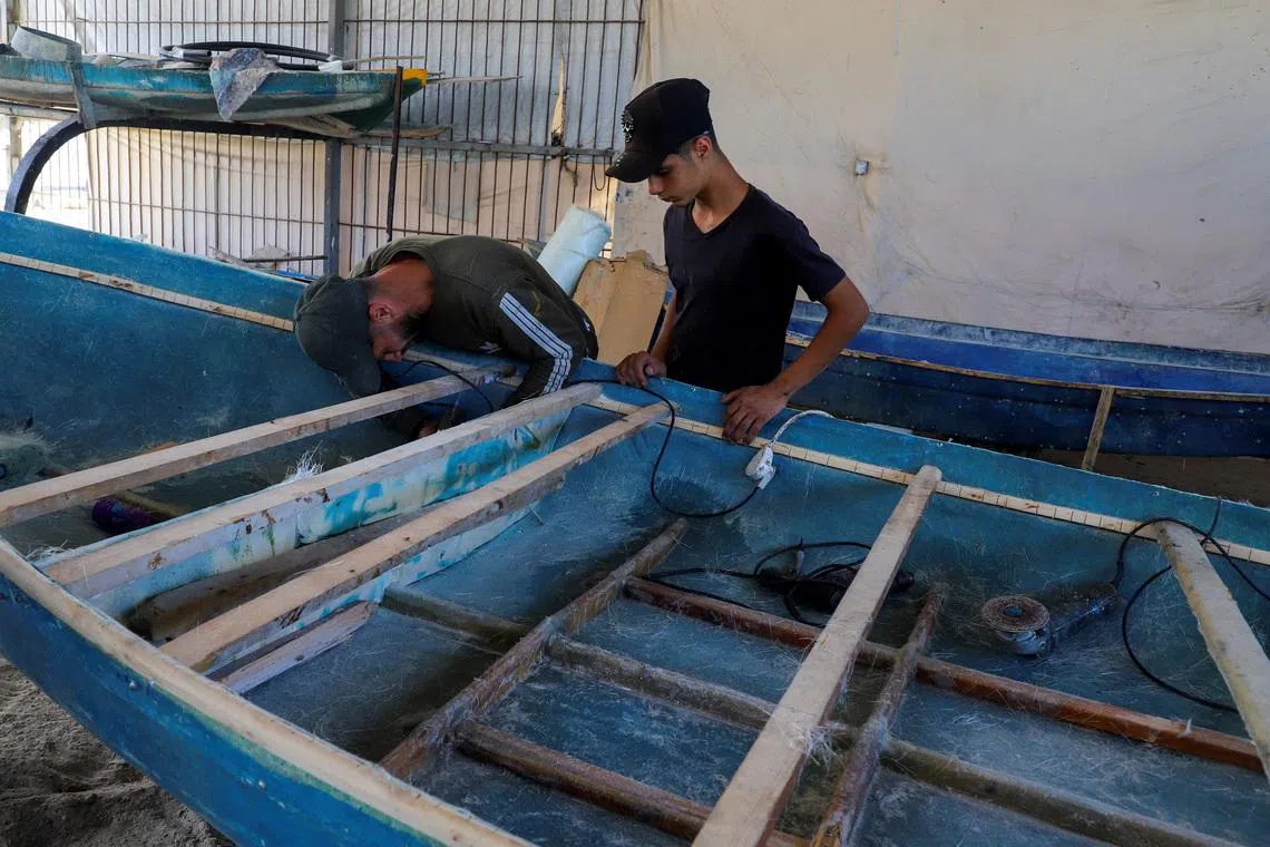 Palestinian workers repairing a skiff damaged in the Israeli offensive, in Gaza City on June 3.