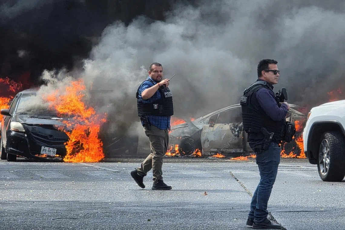 Police officers secure the area where vehicles were set on fire by organized crime members to block a road in Zapopan, Mexico, on Feb 22.