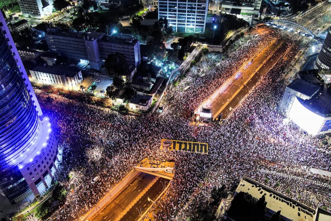 Protesters against the judicial reforms hold a sign in Hebrew that reads "resist", at a demonstration in Tel Aviv.