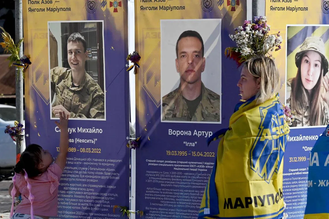 A girl touches a portrait of her late father at an exhibition of fallen Ukrainian servicemen to mark Defenders' Day of Ukraine, in Kyiv, on Sept 28.