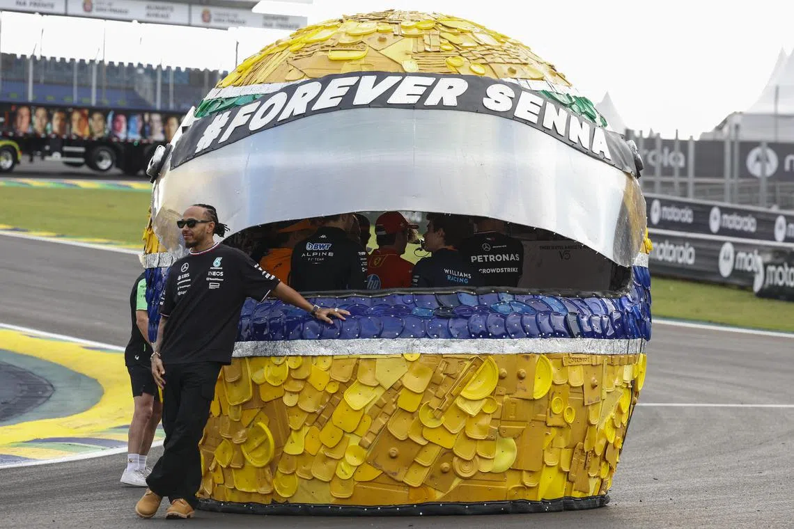 Lewis Hamilton poses next to a helmet made from recycled materials as part of this year's commemorative events marking the 30th anniversary of the death of Brazilian triple world champion Ayrton Senna.