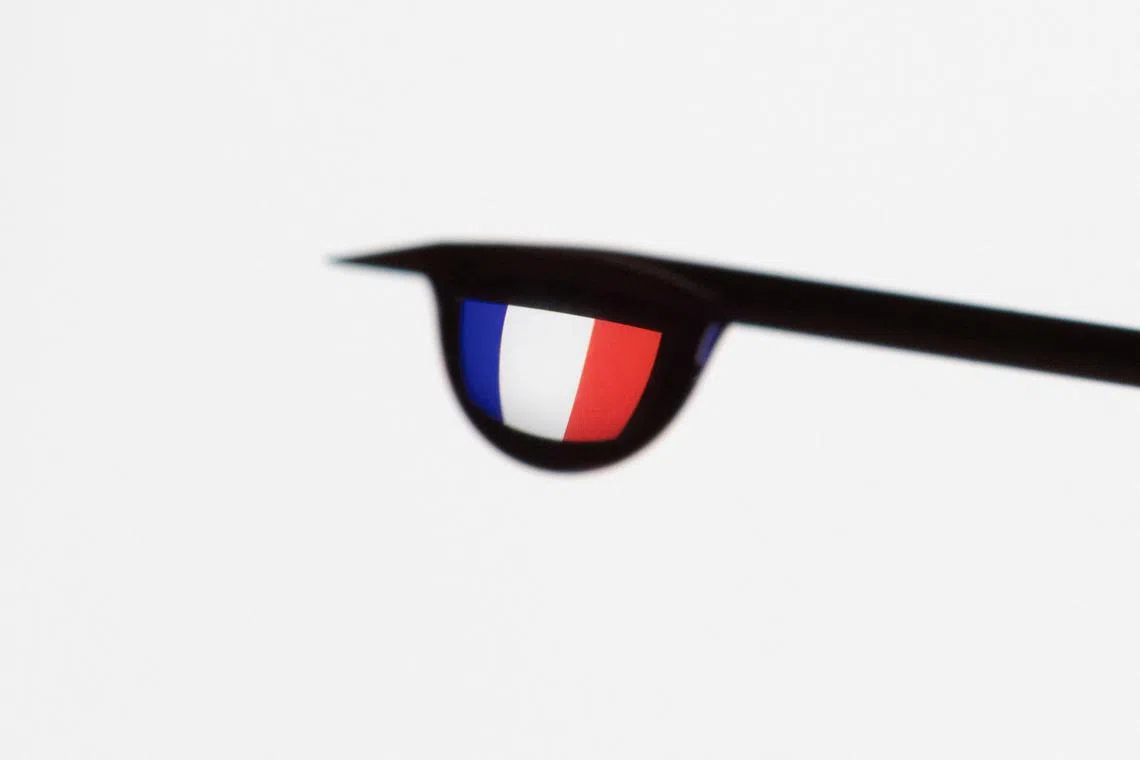 The flag of France is seen reflected in a drop from a syringe needle in this illustration taken December 11, 2021. REUTERS/Dado Ruvic/Illustration/File Photo