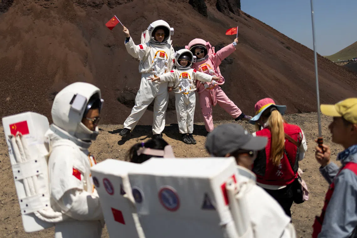 A group of people wearing astronaut costumes pose for pictures at Volcano No. 6 of the Wulanhada Volcano Geopark in Ulanqab, Inner Mongolia Autonomous Region, China, July 26, 2026. In China's northern region of Inner Mongolia, black volcanic rock formations have become a Mars simulator. Visitors rent white or pink spacesuit costumes to pose against the backdrop of barren terrain while food vendors sell astronaut-shaped, strawberry-flavored ice cream. REUTERS/Maxim Shemetov            SEARCH "SHEMETOV CHINA SPACE" FOR THIS STORY. SEARCH "WIDER IMAGE" FOR ALL STORIES.          TPX IMAGES OF THE DAY
