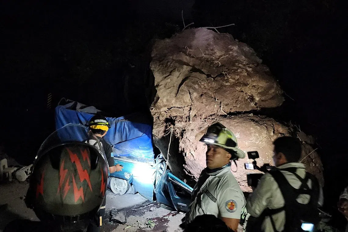 Guatemalan firefighters work beside a vehicle buried under rocks and soil during a landslide, following a quake that shook southern Guatemala, near Santa Maria de Jesus, Guatemala July 8, 2025. Bomberos Voluntarios de Guatemala/Handout via REUTERS