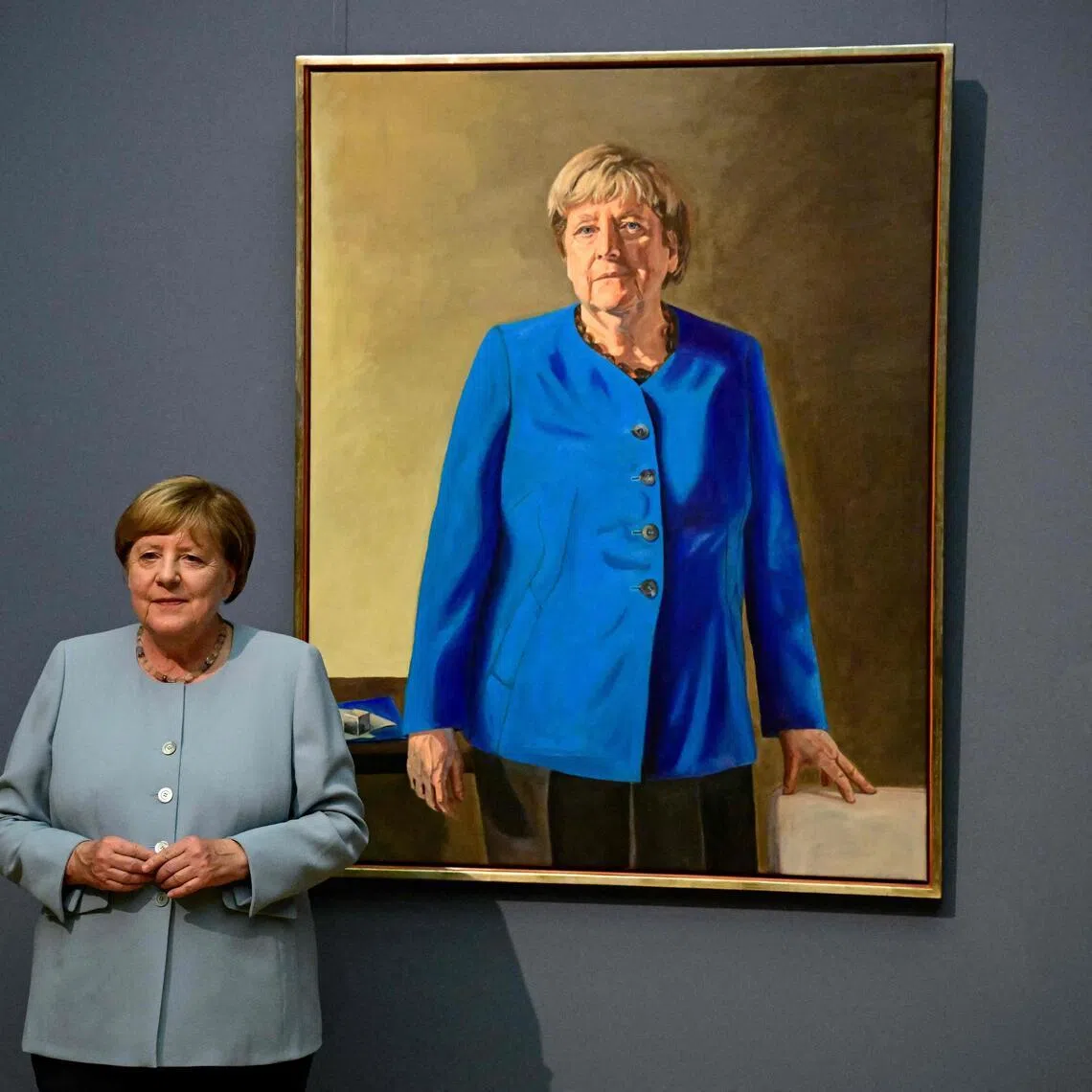 Former German chancellor Angela Merkel stands next to French-German artist Jeremie Queyras’ painting ‘Portrait of former Federal Chancellor Angela Merkel’ at the Bode Museum in Berlin, on June 30.