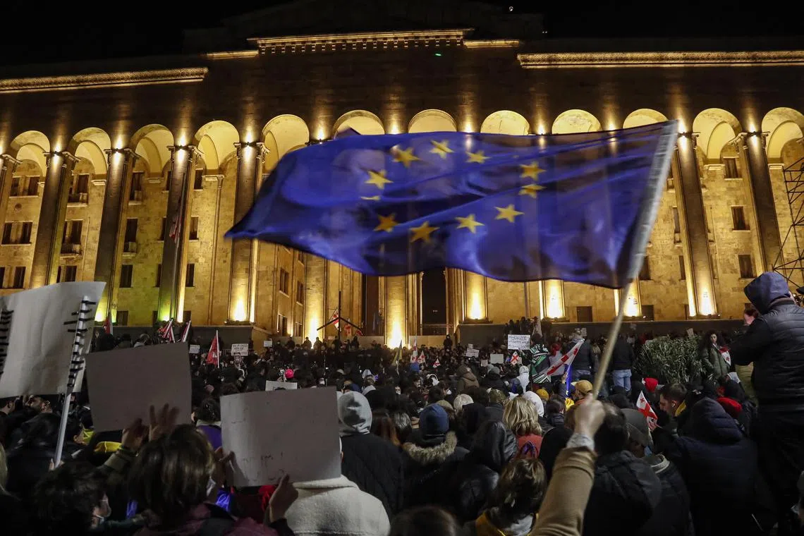 Waving Georgian, Ukrainian and EU flags, people gathered outside the parliament building in the capital Tbilisi to protest.
