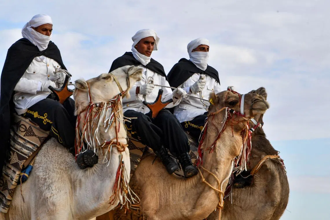 Performers wearing traditional outfits riding camels during a show at the start of the International Sahara Festival on Dec 27, 2023 in Douz, in southern Tunisia. 