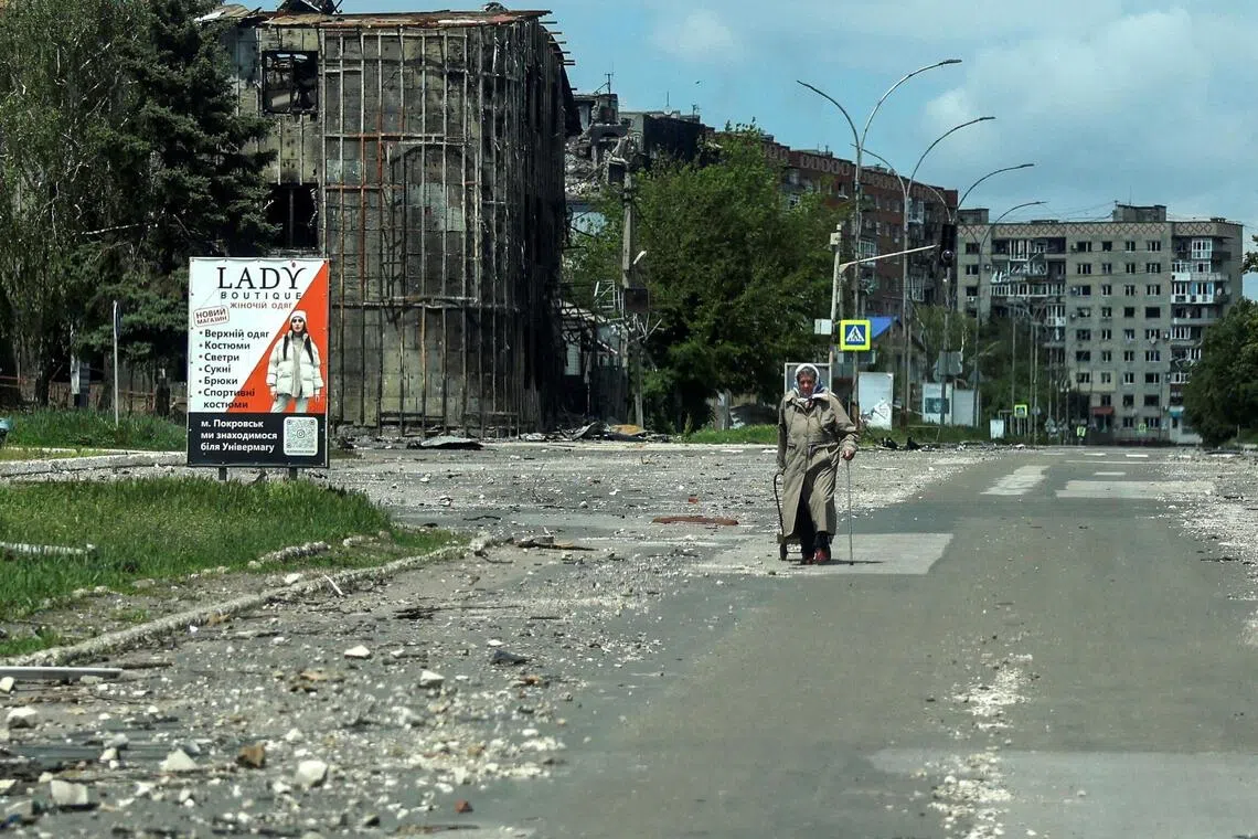 A civilian walks past buildings damaged by Russian military strikes, in the front-line town of Pokrovsk, in Ukraine's Donetsk region.