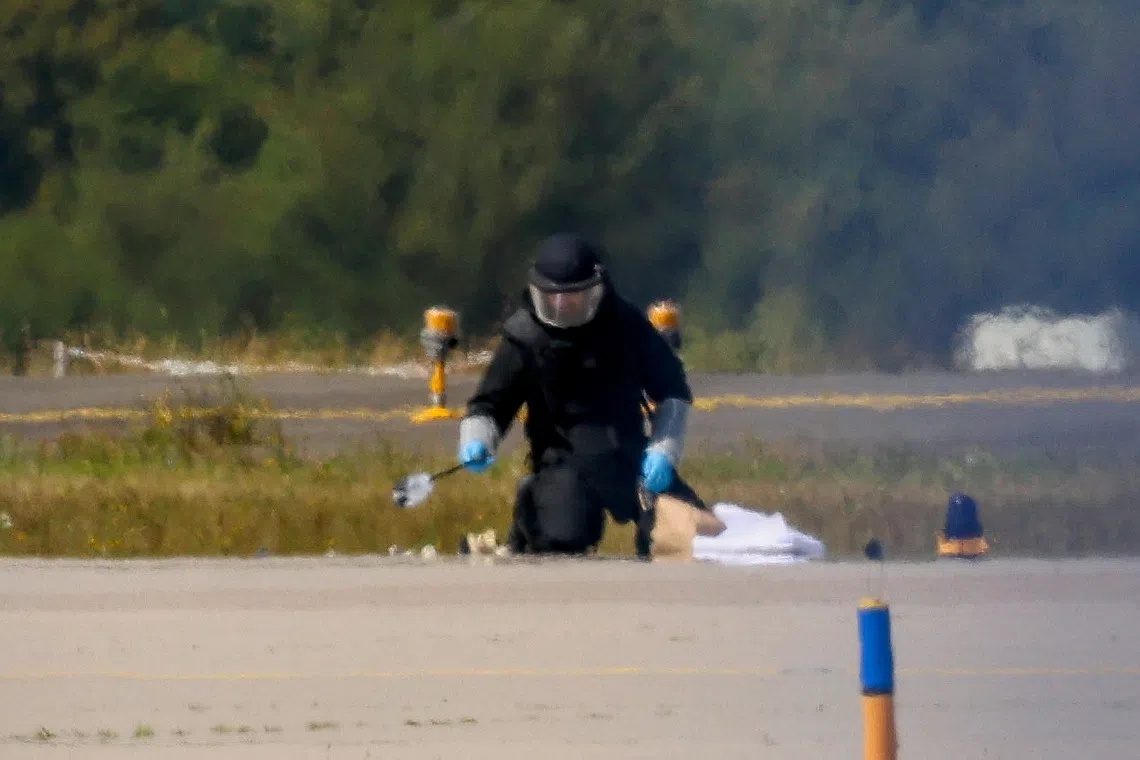 FILE PHOTO: A police officer in protective clothing works at Leipzig/Halle Airport in Schkeuditz, Germany, August 5, 2026, after the police said explosives experts examined a drone near a runway, and after a DHL cargo aircraft hit an unknown object as it was climbing away from the airport overnight, prompting an unscheduled landing in Hanover, according to a source familiar with the incident. REUTERS/Axel Schmidt/File Photo