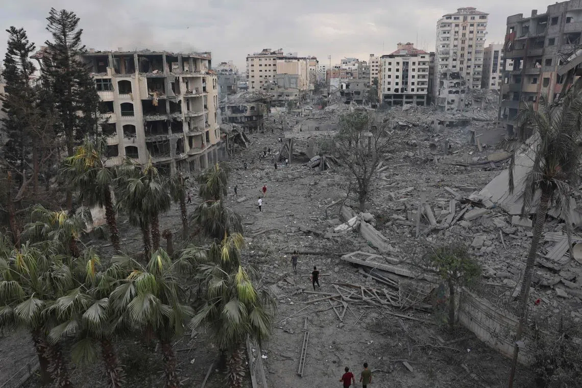 Palestinians inspect the massive destruction from Israeli airstrikes in Gaza City's al-Rimal district, on Oct 10, 2023. 