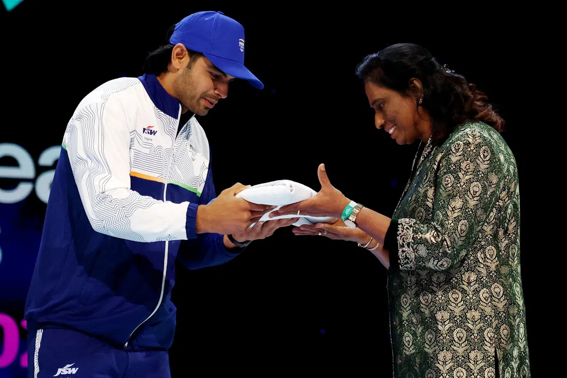President of the Indian Olympic Association PT Usha hands the flag to India’s Neeraj Chopra during the closing ceremony.