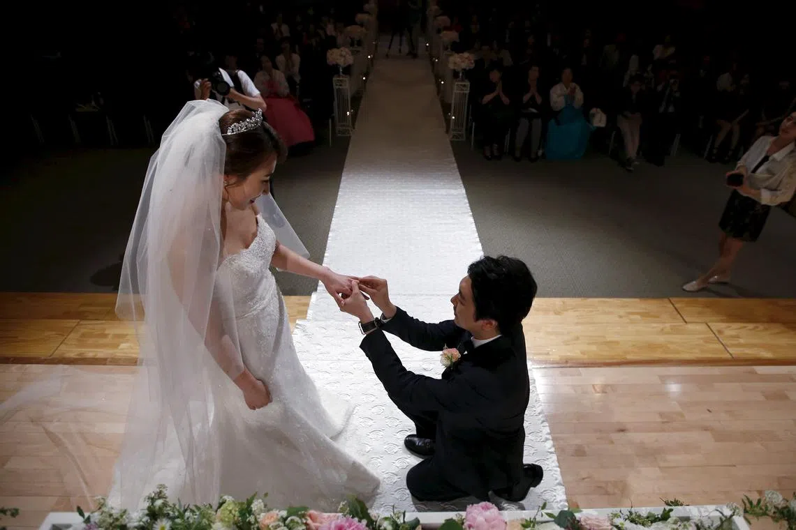 FILE PHOTO: A groom puts a wedding ring on his bride's finger during a wedding ceremony at a budget wedding hall at the National Library of Korea in Seoul, South Korea, May 16, 2015. REUTERS/Kim Hong-Ji