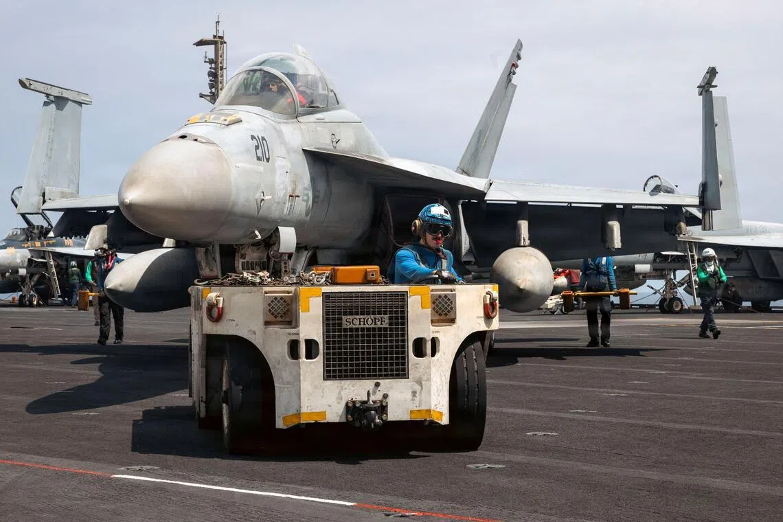 A US Navy sailor moves an F/A-18F Super Hornet aircraft across the flight deck of the aircraft carrier USS Gerald R. Ford on March 18.