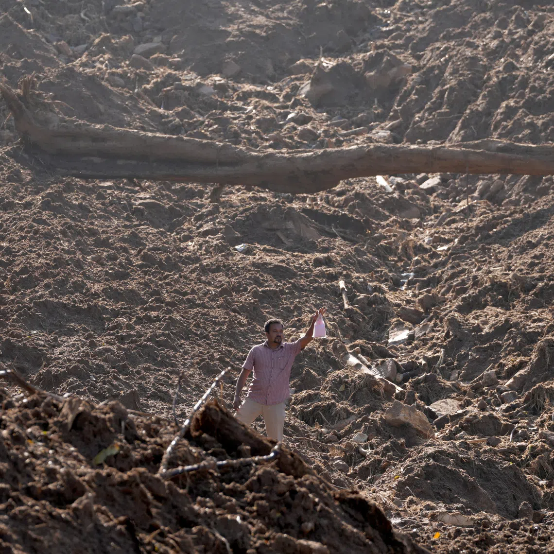 A man holds up a food packet as he moves through mud after landslides triggered by heavy rainfall following Cyclone Ditwah, in Mawathura in Kandy district, Sri Lanka, December 3, 2025. REUTERS/Thilina Kaluthotage
