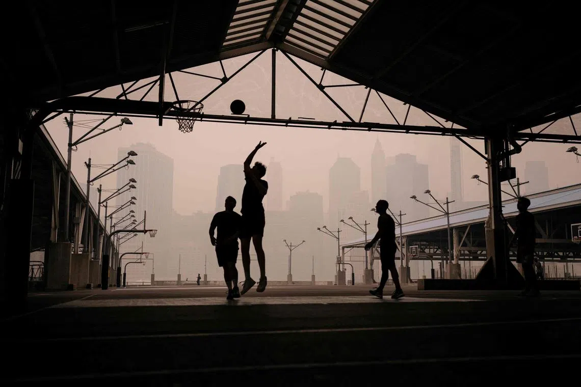 People play outdoor basketball in Brooklyn Bridge Park as the Lower Manhattan skyline is obscured by hazy skies on June 7, 2023 in New York City. 