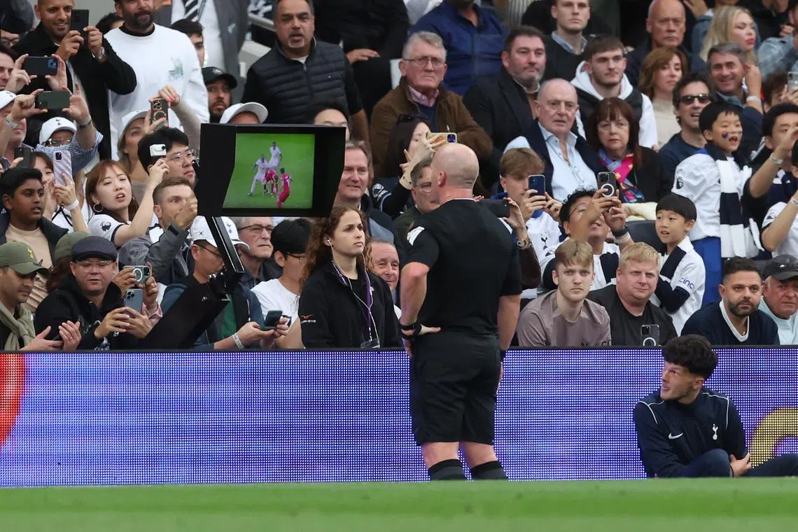 Referee Simon Hooper (centre) checks the VAR display before giving a red card to Liverpool's Curtis Jones.