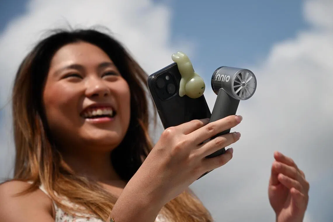 A woman holding the NNIO U-Mini High Speed Portable Handheld Fan. The compact 103g fan is smaller than the average smartphone and is highly portable.