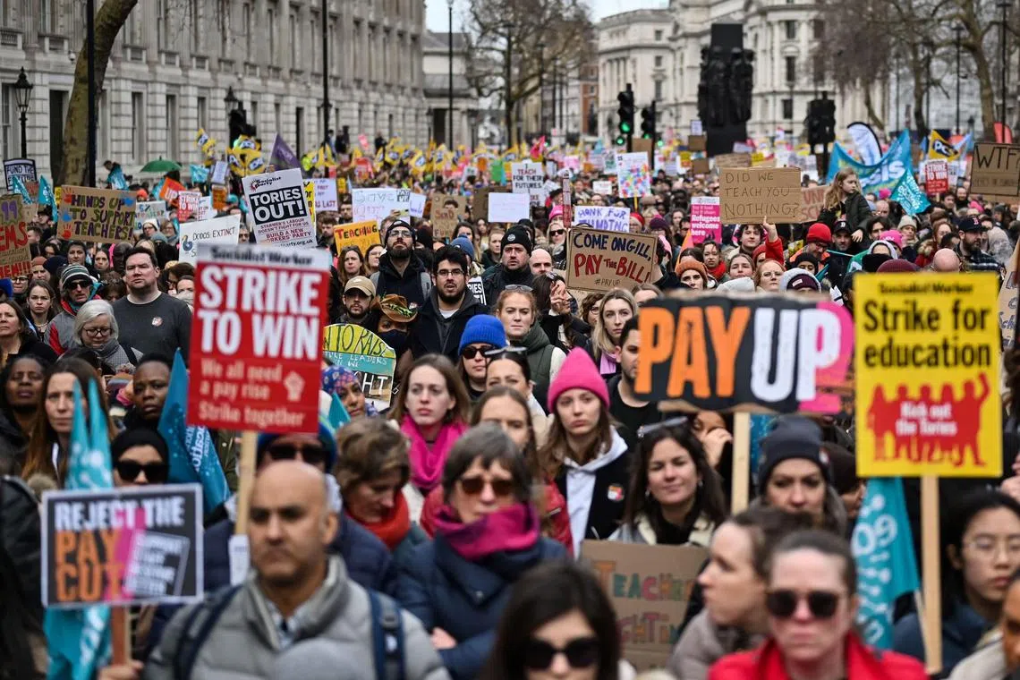 TOPSHOT - Teachers hold placards and flags while shouting slogans as part of a national strike day in February.