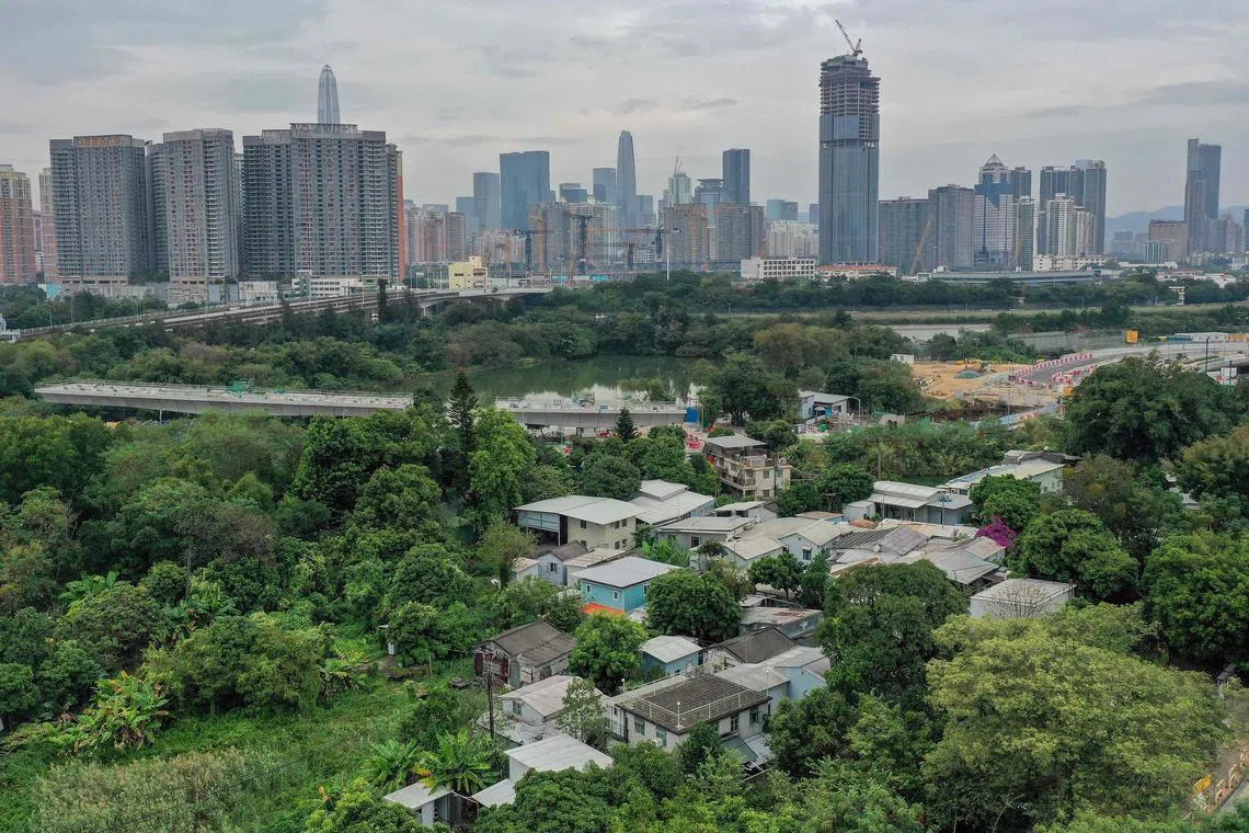 This photo taken on November 10, 2024 shows an aerial view of the hundred-year-old village of Ha Wan Tsuen near San Tin in northern Hong Kong, on the border with the Chinese city of Shenzhen. For almost half a century, Kwok Hoi-yin's humble cottage on Hong Kong's border with mainland China was surrounded by leagues of fishponds and green fields, buffering the modern highrises of megacity Shenzhen to the north. In recent years his village has shrunk, nibbled away by roads and bridges as the government claims land for its Northern Metropolis project, an ambitious plan to urbanise the border area that has proceeded despite concerns from locals and environmentalists. (Photo by Peter PARKS / AFP) / TO GO WITH: HONG KONG-CHINA-ENVIROMENT-URBAN-PLANNING, FOCUS by Xinqi SU