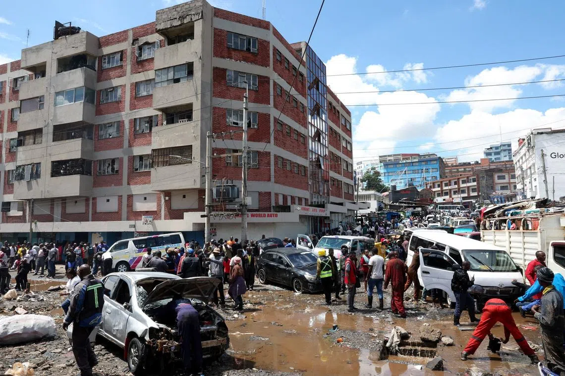 FILE PHOTO: People stand around destroyed vehicles following flash floods caused by heavy rainfall in the Grogan area, popular for automotive workshops and secondhand spare parts, in downtown Nairobi, Kenya, March 7, 2026. REUTERS/Monicah Mwangi/File Photo