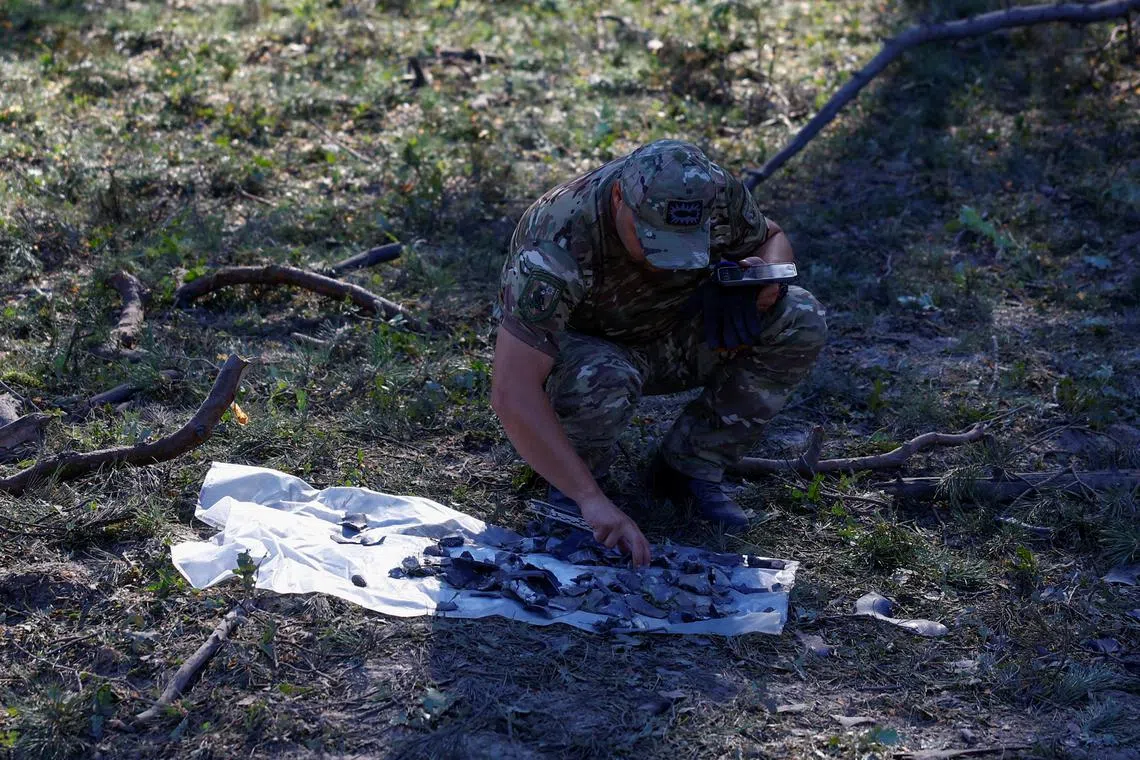 A police officer inspecting pieces of a missile found in a crater, after an attack by Russia in Ukraine's Kyiv region, on Aug 6.