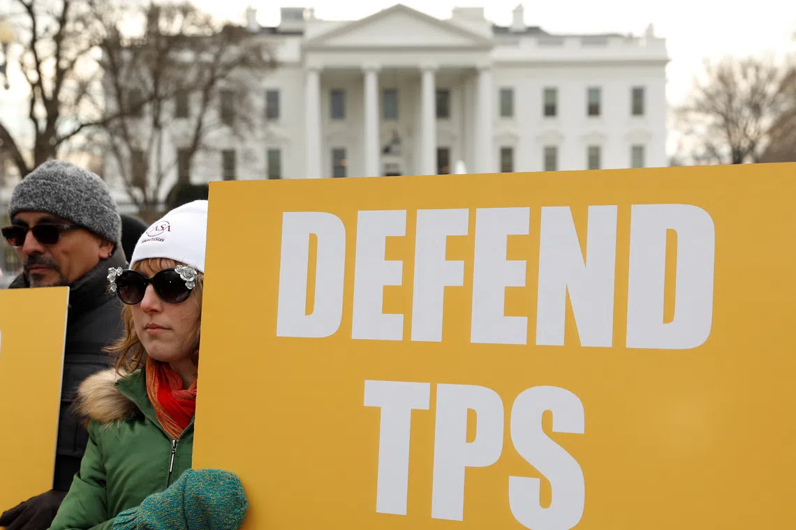 FILE PHOTO: Demonstrators hold signs advocating for Temporary Protected Status (TPS) in front of the White House in Washington, D.C., U.S., January 8, 2018. REUTERS/Kevin Lamarque/File Photo