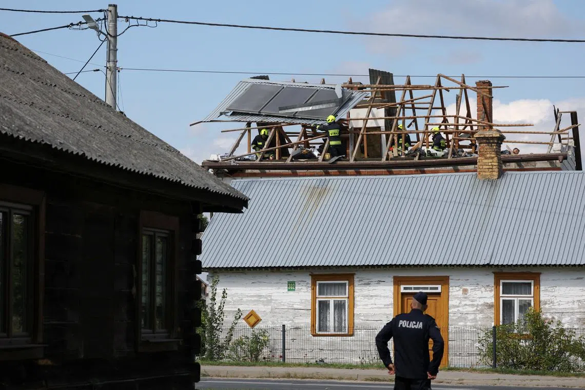 A police officer stands below as firefighters work on the destroyed roof of a house, after Russian drones violated Polish airspace during an attack on Ukraine, with some being shot down by Poland with the backing from its NATO allies, in Wyryki, Lublin Voivodeship, Poland, September 10, 2025. REUTERS/Kacper Pempel