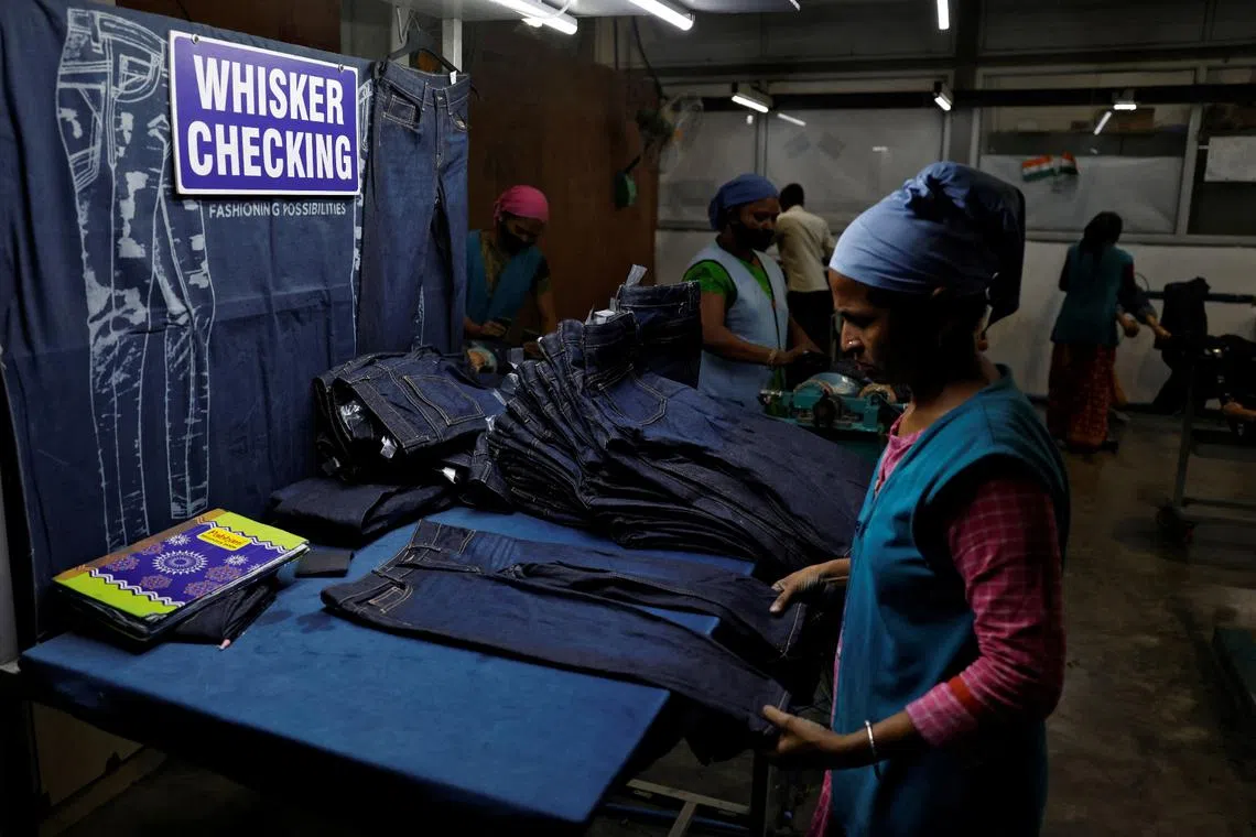 A worker making final checks on jeans before packaging in a garment manufacturing unit on the outskirts of Ahmedabad, India, on Aug 5.