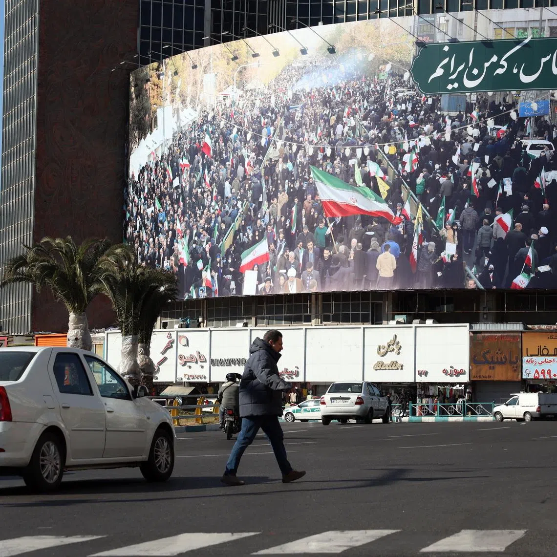 An Iranian walk next to a billboard reading at the Valiasr square in a street in Tehran on Jan 16.