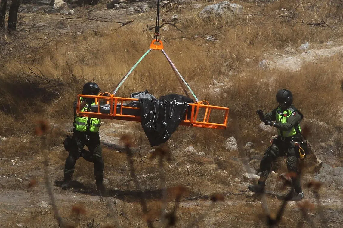 Forensic experts work with several bags of human remains extracted from the bottom of a ravine by a helicopter, which were abandoned at the Mirador Escondido community in Zapopan, Jalisco state, Mexico on May 31, 2023. The Jalisco Prosecutor's Office is investigating to find out if the remains belong to the 7 call center workers who disappeared on their way to work in recent days. (Photo by ULISES RUIZ / AFP)