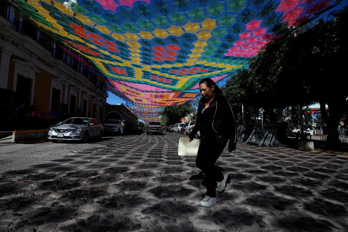 A woman walks under a 14,000 square meters "woven sky" made of raffia, considered the world's largest, covering the main streets of Etzatlan, Mexico, on November 1, 2022. 