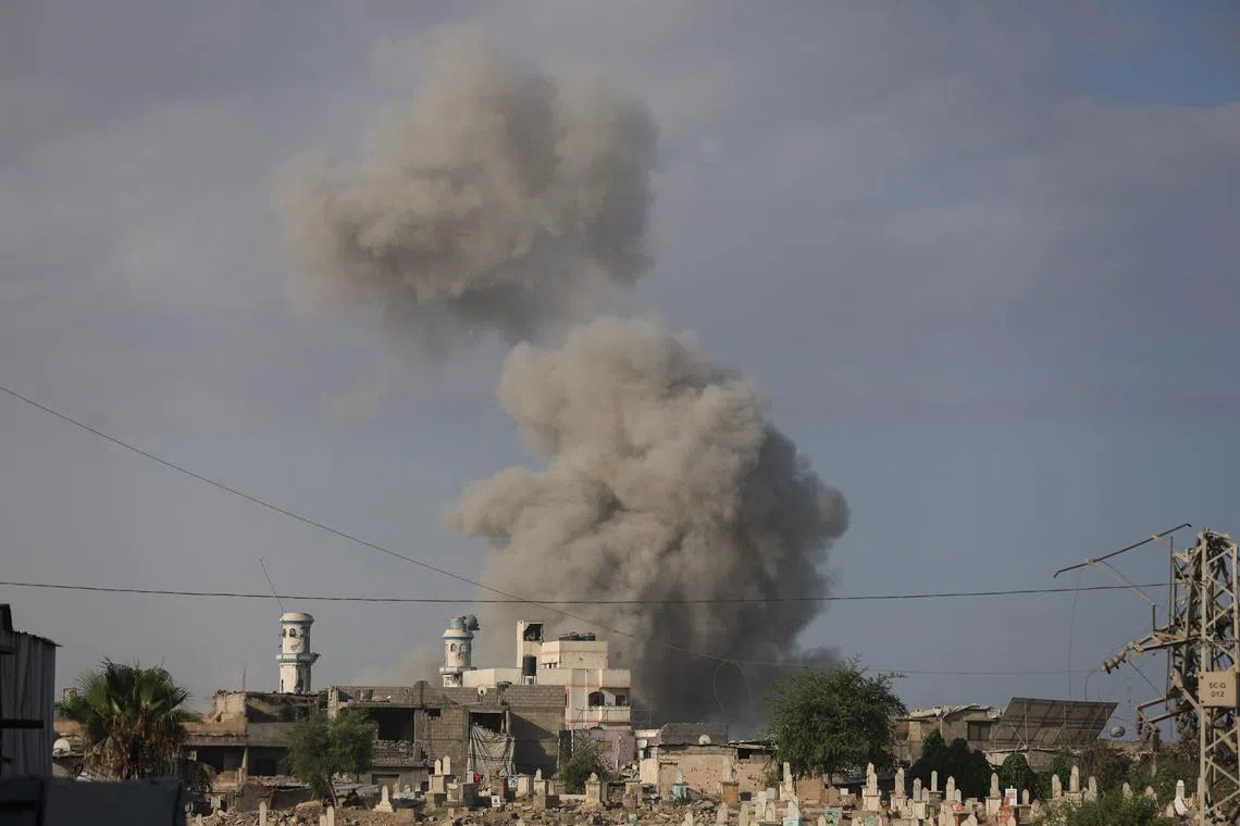 Tombstones are seen in the foreground as smoke rises following an explosion during an Israeli operation in Gaza City, August 28, 2025. REUTERS/Dawoud Abu Alkas