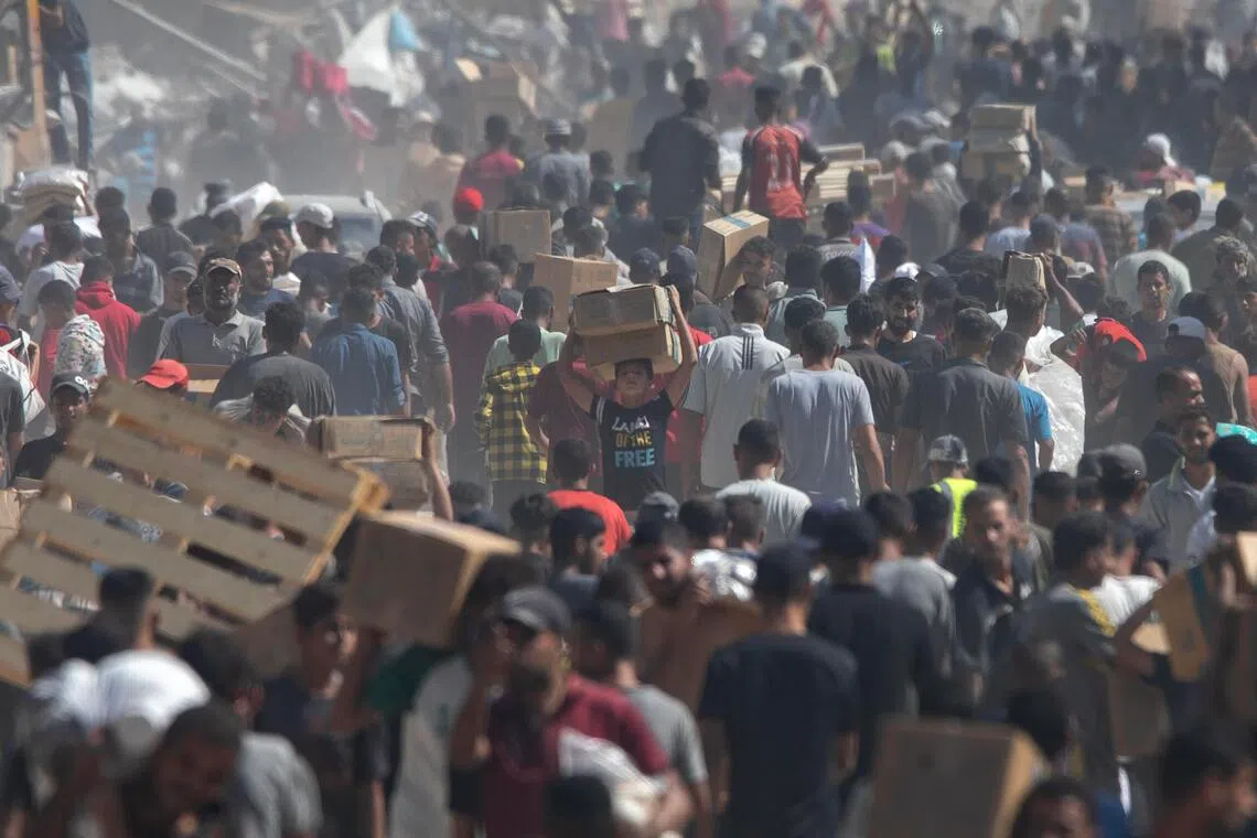 Palestinians carry aid supplies that arrived by trucks in Khan Yunis in the southern Gaza Strip, on Oct 11,  2025.