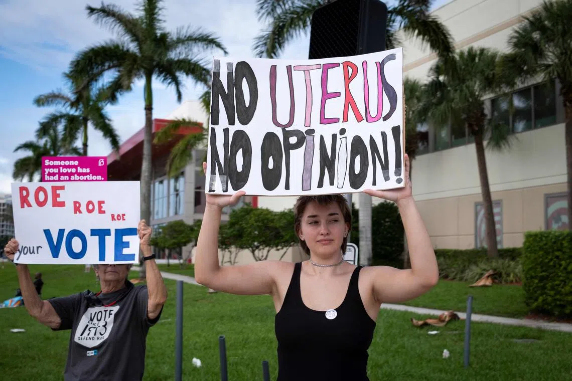 (FILES) People hold signs during a pro-abortion rights rally on the second anniversary of the US Supreme Court ruling to overturn Roe v. Wade, in West Palm Beach, Florida, on June 24, 2024. Abortion restrictions in Florida have led to care being delayed or denied outright in complicated pregnancies, according to a report issued on September 17, 2024. The report, published by the nonprofit NGO Physicians for Human Rights, asserts Florida's abortion restrictions "endanger both clinicians and pregnant patients in the state." (Photo by Marco BELLO / AFP)