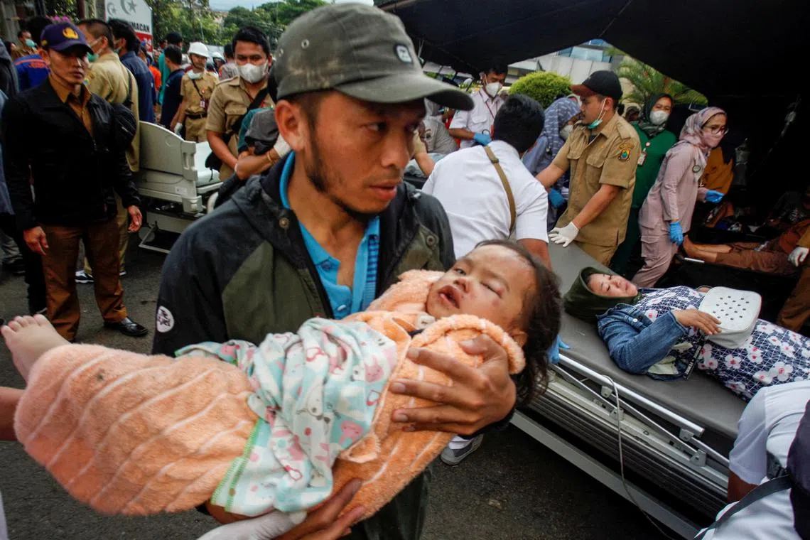 A man carries an injured child to receive treatment at a hospital, after an earthquake hit in Cianjur, West Java province, Indonesia, Nov 21, 2022.