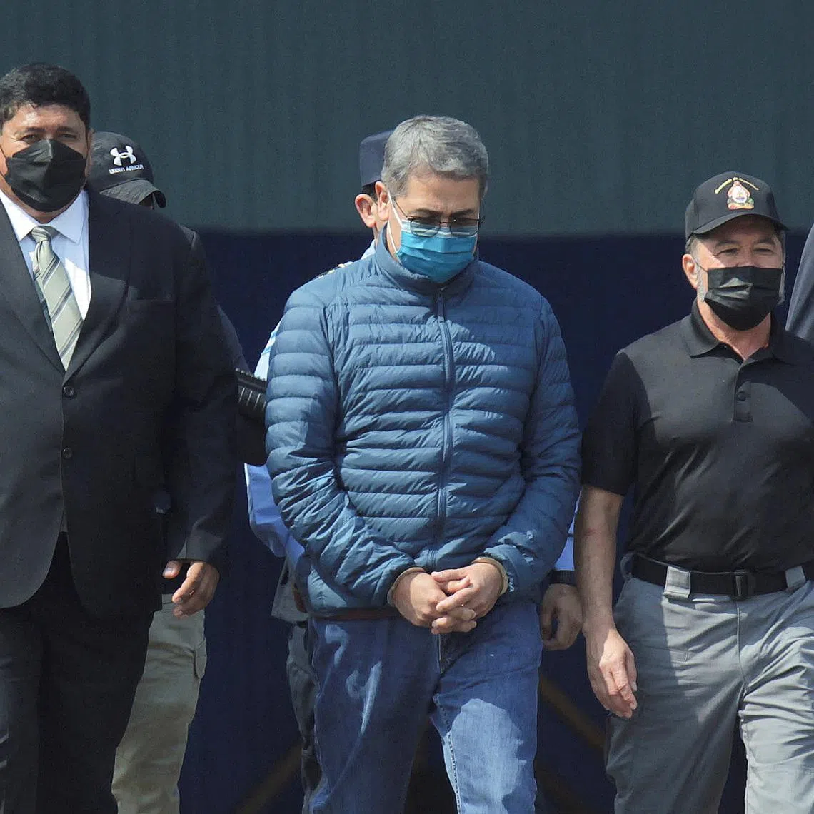 FILE PHOTO: Honduras former President Juan Orlando Hernandez is escorted by authorities as he walks towards a plane of the U.S. Drug Enforcement Administration (DEA) for his extradition to the United States, to face a trial on drug trafficking and arms possession charges, at the Hernan Acosta Mejia Air Force base in Tegucigalpa, Honduras April 21, 2022. REUTERS/Fredy Rodriguez/File Photo