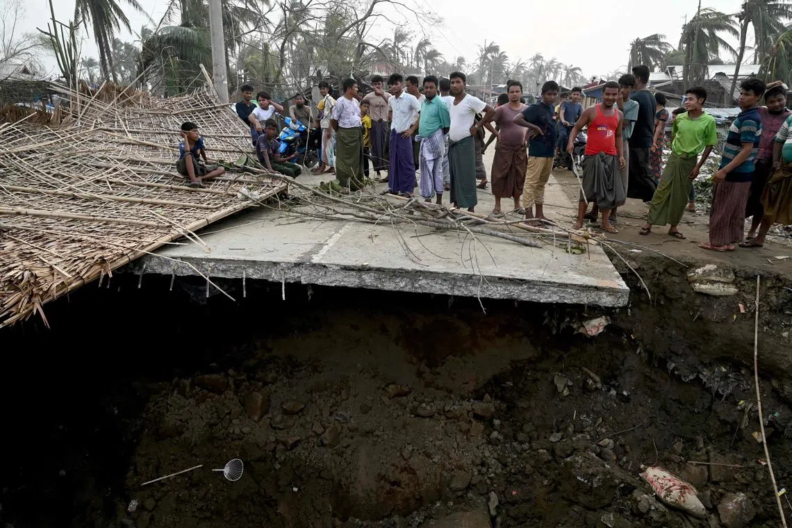 TOPSHOT - Local residents stand on a broken bridge at the Khaung Dote Khar Rohingya refugee camp in Sittwe, on May 15, 2023, after cyclone Mocha made a landfall. Cyclone Mocha made landfall between Cox's Bazar in Bangladesh and Myanmar's Sittwe carrying winds of up to 195 kilometres (120 miles) per hour, the biggest storm to hit the Bay of Bengal in more than a decade (Photo by Sai Aung MAIN / AFP)