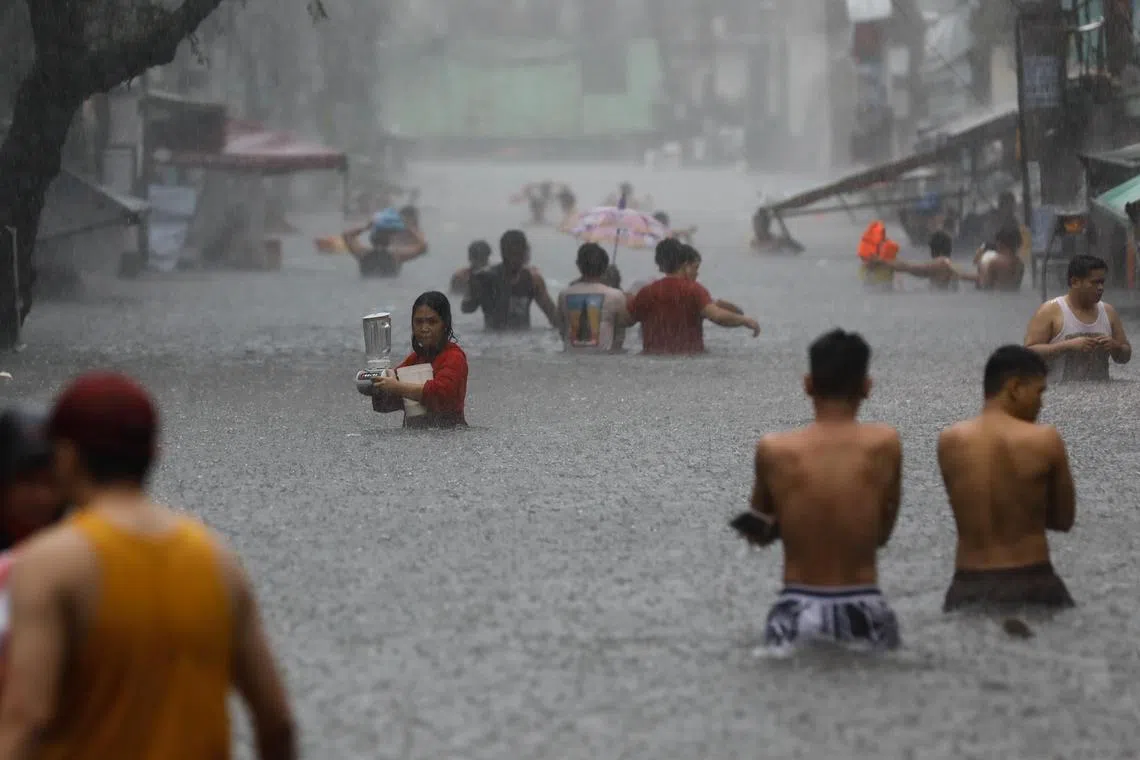 epa11493375 Residents walk in a flooded area following monsoon rainfall in Quezon City, Metro Manila, Philippines, 24 July 2024.  Monsoon rains caused by typhoon Gaemi resulted in flooding in Metro Manila and nearby provinces, as it is forecast to be headed in the general direction of Taiwan as it moves out of Philippine territory.  EPA-EFE/ROLEX DELA PENA
