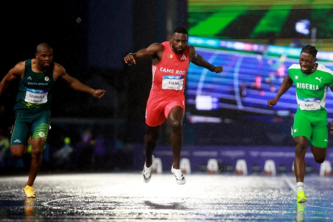 Cameroon’s Emmanuel Eseme (in red) crosses the finish line to win the men’s 100m final at the Commonwealth Games.