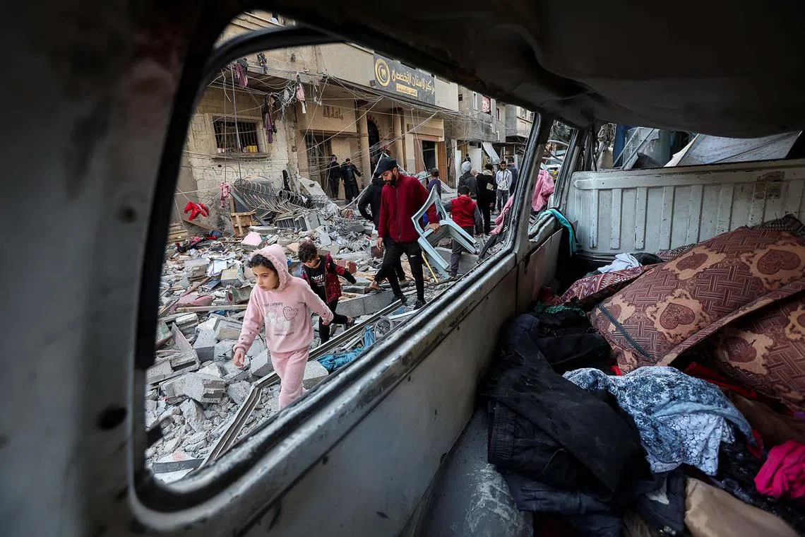 Palestinians walking at the site of an Israeli strike on a house, amid the ongoing conflict between Israel and Hamas, in Nuseirat in the central Gaza Strip, Jan 9, 2025. 